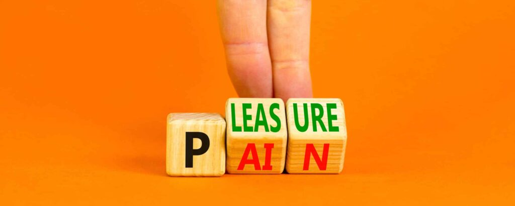 Pain or pleasure symbol. Concept words Pain or Pleasure on wooden cubes. Businessman hand. Beautiful orange table orange background. Business and pain or pleasure concept. Copy space.