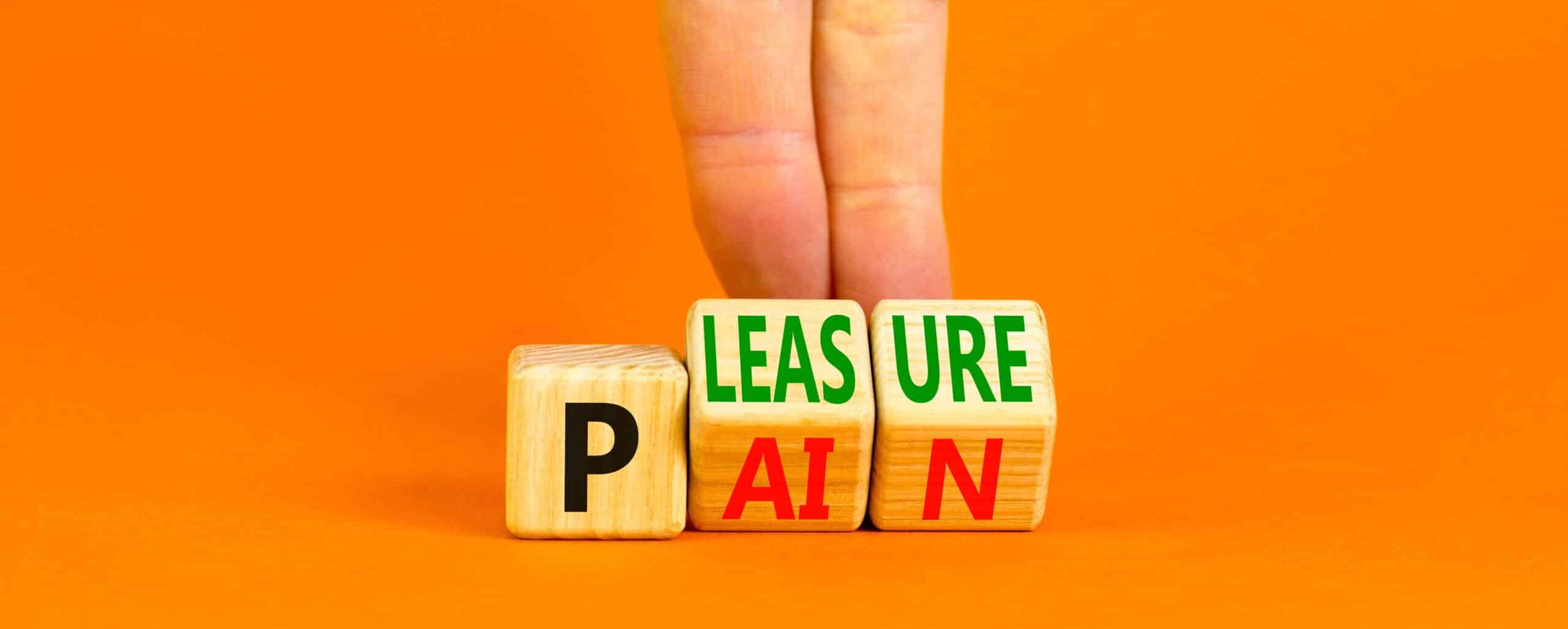 Pain or pleasure symbol. Concept words Pain or Pleasure on wooden cubes. Businessman hand. Beautiful orange table orange background. Business and pain or pleasure concept. Copy space.
